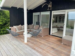 A covered outdoor seating area with wicker furniture and a glass door leading to an interior space. - 5 Star Holiday Home in Hillerod (Hillerod)