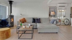 A cozy living room with a fireplace, a sofa, a coffee table, and a bicycle in the background. - 5 Star Holiday Home in Hillerod (Hillerod)