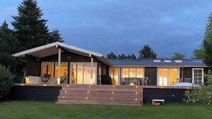 A modern house with a covered patio, large windows, and a well-maintained lawn. - 5 Star Holiday Home in Hillerod (Hillerod)