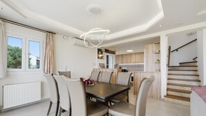 Un coin repas avec une table et des chaises, une cuisine à l’arrière-plan et un escalier.