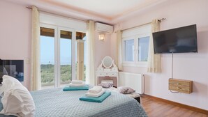 Une chambre à coucher comprenant un lit, une télévision, une commode, une fenêtre et une vue sur l’extérieur.