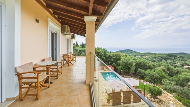 Un balcon avec une piscine, des meubles en bois et une vue sur la campagne.