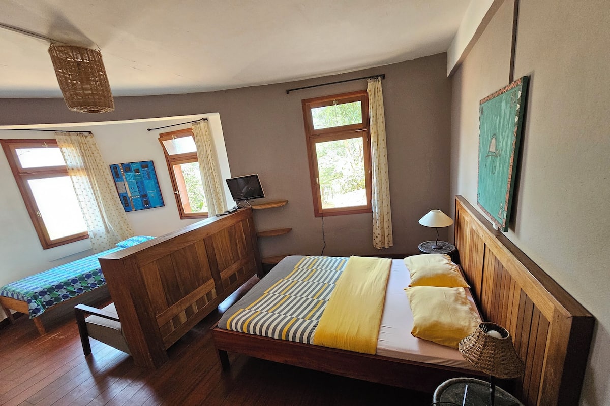 Un dormitorio con cama y banco de madera, un escritorio pequeño y un televisor.
