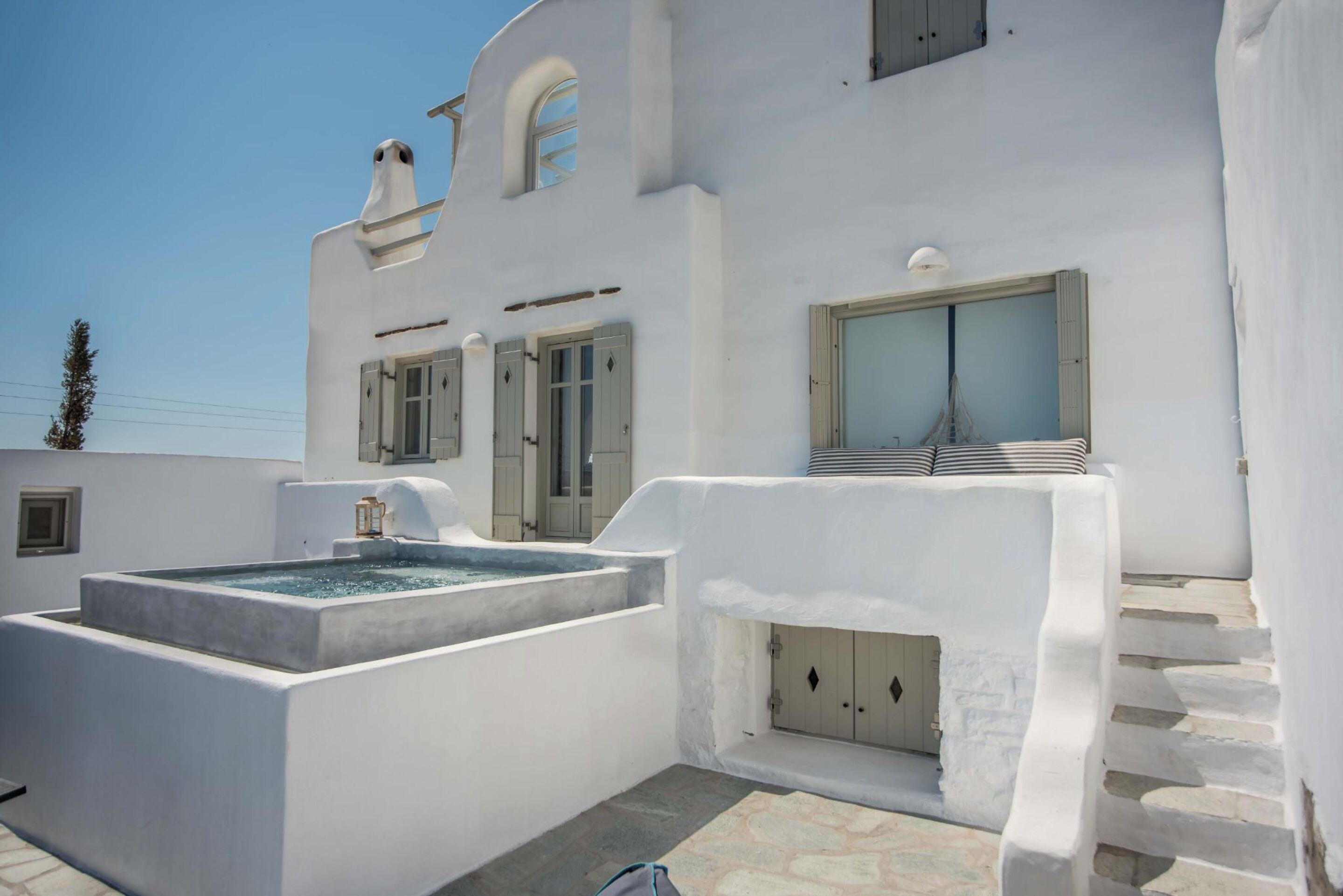 A white building with a pool, a staircase, and a door.