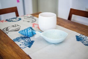 A table with a white tablecloth featuring blue and red patterns, a white ceramic cup, and a white ceramic bowl with a blue handle. - Villa Pisti by Apleton Villas Paros (Paros)