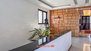 Un intérieur moderne avec un comptoir d’accueil, un mur recouvert de panneaux en bois et une statue.