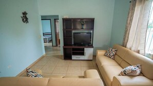 Ein Wohnzimmer mit einer Sofagarnitur, einem Fernsehschrank und einer Tür zu einem anderen Raum.