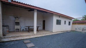Um edifício com um pátio ladrilhado, um forno de tijolos e uma mesa com cadeiras.