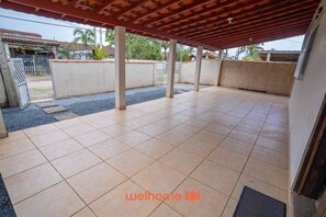 An open patio with tiled flooring, a wooden pergola, and a view of the surrounding neighborhood.