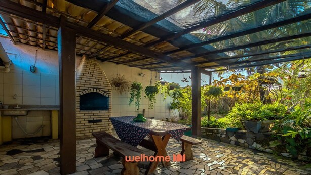 Eine Terrasse im Freien mit einem Backofen aus Ziegeln, einem Tisch mit gemustertem Tuch und hängenden Pflanzen.