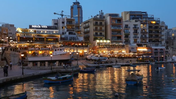 A waterfront cityscape with buildings, a prominent tower, and boats docked along the quay. - Spacious Paceville fully equipped home w/WIFI (St. Julian`s)