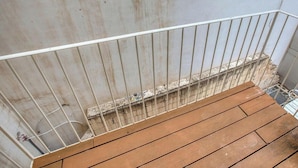A wooden deck with a metal railing, a concrete wall, and a window in the background. - Spacious Paceville fully equipped home w/WIFI (St. Julian`s)
