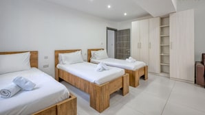 A hotel room with three wooden beds, a wardrobe, and a bathroom door. - Spacious Paceville fully equipped home w/WIFI (St. Julian`s)