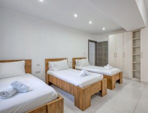 A hotel room with three wooden beds, a wardrobe, and a bathroom door.