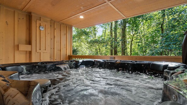A hot tub area with wooden walls and a view of a forest. - Cabin On A Hill 2 Bedroom Cabin (Cosby)