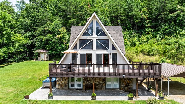 A large, two-story house with a prominent triangular roof, a covered porch, and a small adjacent structure. - Smoky Everest 4 Bedroom Chalet (Newport)
