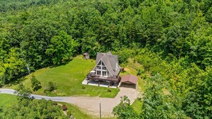 An aerial view of a house surrounded by dense forest, with a large lawn and a driveway leading to the main entrance. - Smoky Everest 4 Bedroom Chalet (Newport)