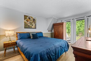 A bedroom with a large bed, a nightstand, a wooden wardrobe, and a painting on the wall. - Smoky Everest 4 Bedroom Chalet (Newport)