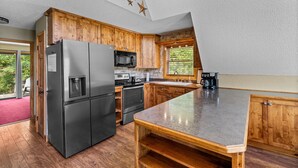A kitchen with wooden cabinets, a stainless steel refrigerator, a microwave, and a coffee maker. - Smoky Everest 4 Bedroom Chalet (Newport)