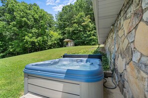A hot tub in a backyard with a stone wall and a small shed in the background. - Smoky Everest 4 Bedroom Chalet (Newport)