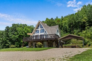 A two-story house with a balcony, a covered porch, and a gravel driveway. - Smoky Everest 4 Bedroom Chalet (Newport)