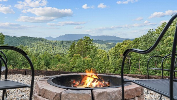 A fire pit with a clear view of a forested mountain range.