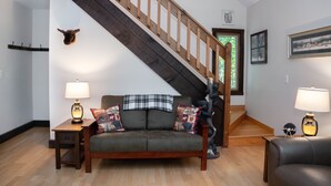 A living room with a wooden staircase, a sofa with decorative pillows, and two lamps on side tables.