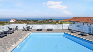 A swimming pool with lounge chairs and a view of the sea. - 5 Star Holiday Home in Allinge (Allinge)