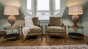 Et værelse med to lænestole, et vindue og to lamper på små borde.