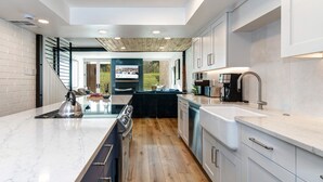 A modern kitchen with a central island, wooden flooring, and a view of the outdoors. - Ski Captain Molly 3 Bedroom Condo (Park City)