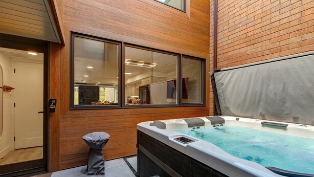 A hot tub in an outdoor area with wooden walls and a large window. - Ski Captain Molly 3 Bedroom Condo (Park City)