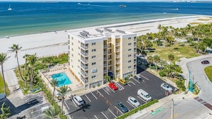 A multi-story hotel with a rooftop pool, parking lot, and a view of the beach and ocean. - Vacation Villas #131 2 Bedroom Condo (Fort Myers Beach)