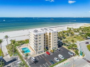 A multi-story hotel with a rooftop pool, parking lot, and a view of the beach and ocean. - Vacation Villas #131 2 Bedroom Condo (Fort Myers Beach)