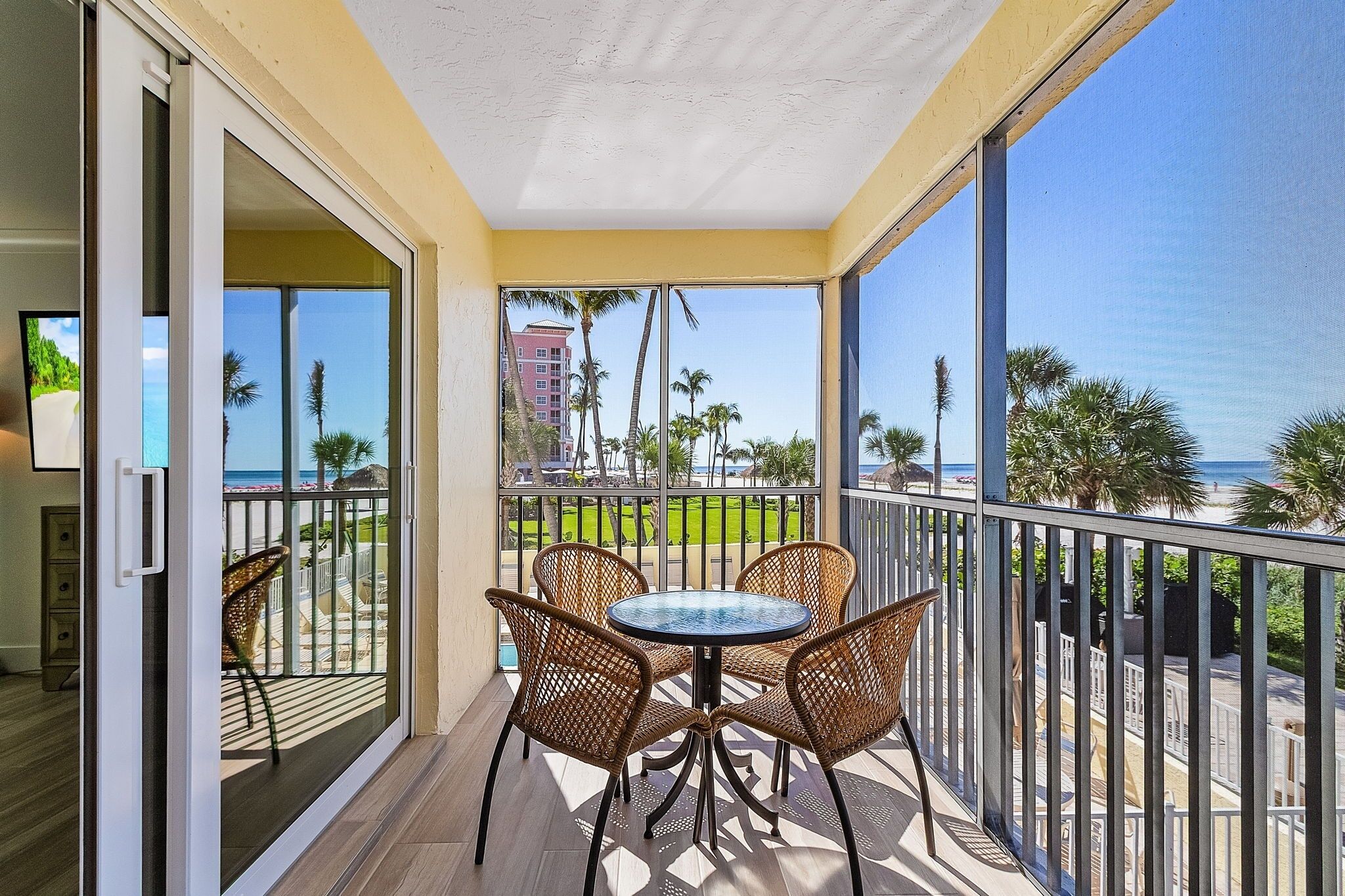 A balcony with a table and chairs, a view of the ocean, and a building in the background.