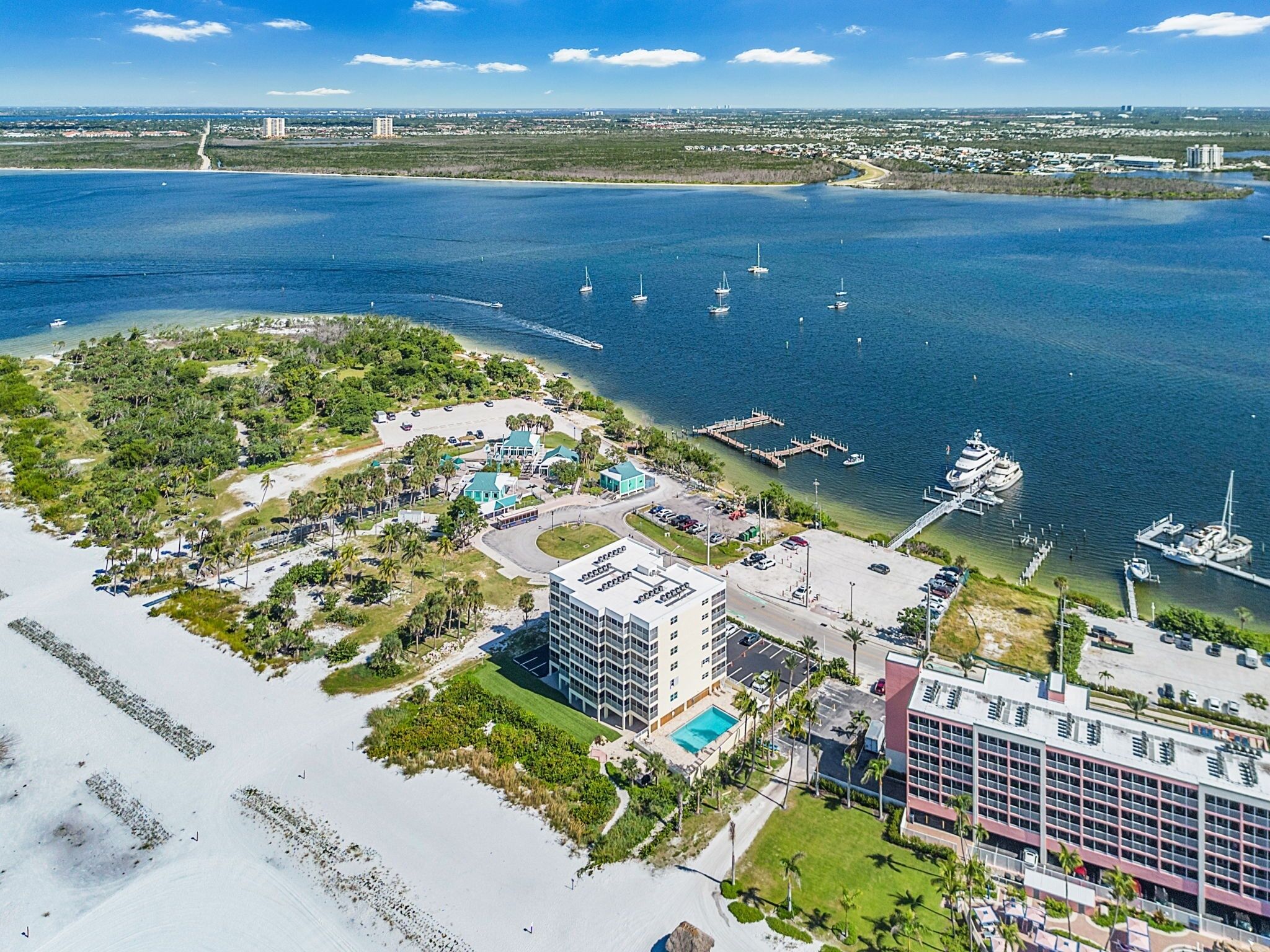 A coastal hotel with a pool, multiple buildings, and a marina with boats.