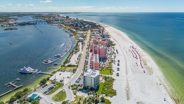 An aerial view of a coastal city with a marina, beachfront hotels, and a bridge connecting to an island. - Vacation Villas #131 2 Bedroom Condo (Fort Myers Beach)
