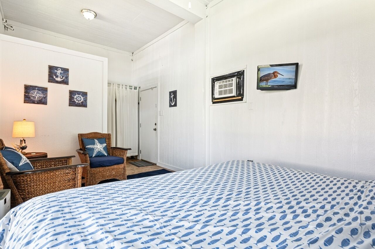 A room with a bed, a chair, a lamp, and wall decorations including nautical-themed artwork.