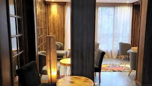 Ein modernes Interieur mit einem runden Holztisch, schwarzen Ledersesseln, einem Bücherregal und einem Fellteppich auf dem Boden.