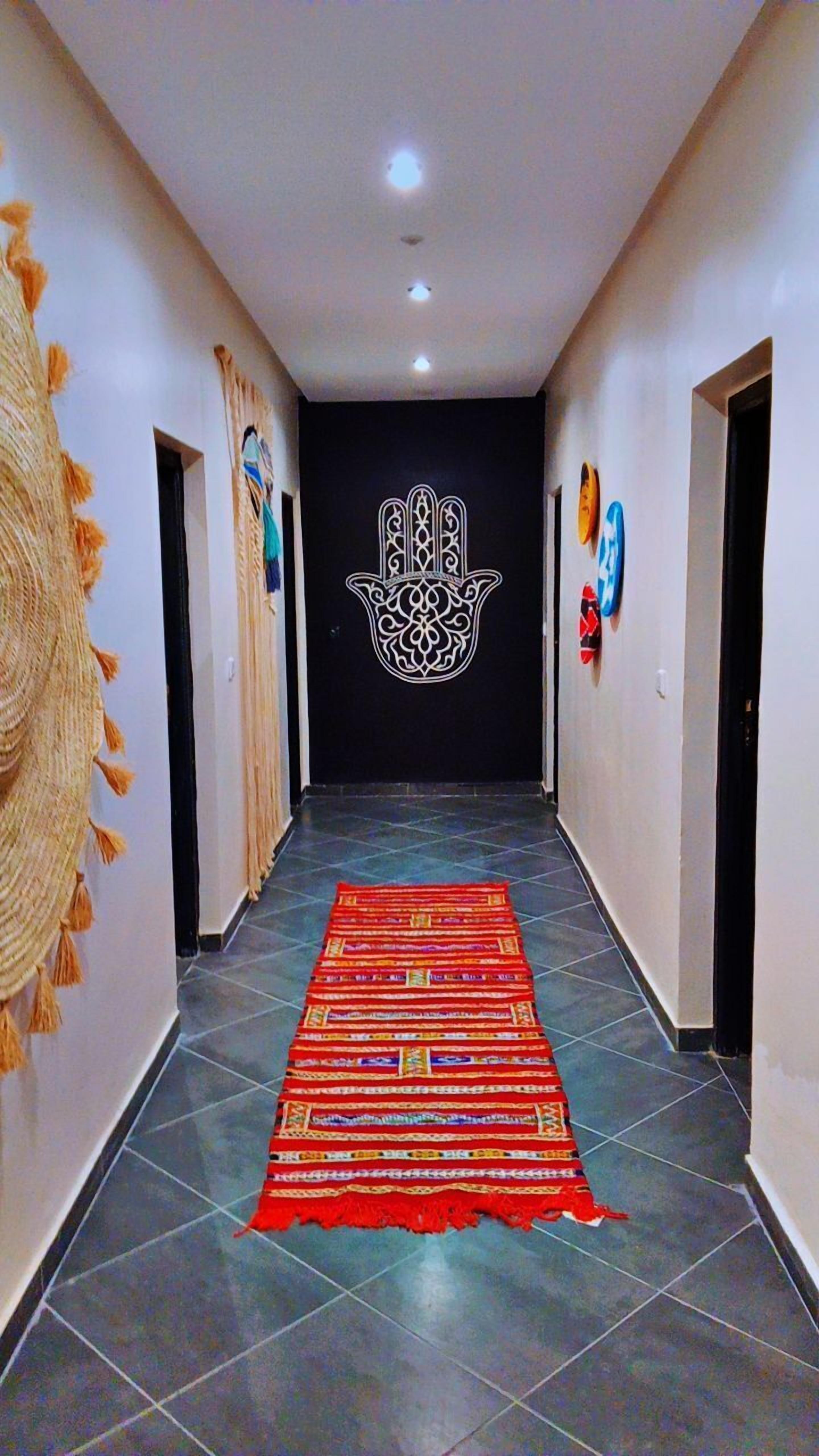 A hallway with a patterned carpet, a decorative wall hanging, and a central emblem.