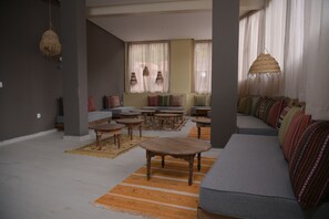 A spacious living room with a gray sofa, wooden tables, and patterned cushions. - Perle de Setti-Fadma (Sti Fadma)