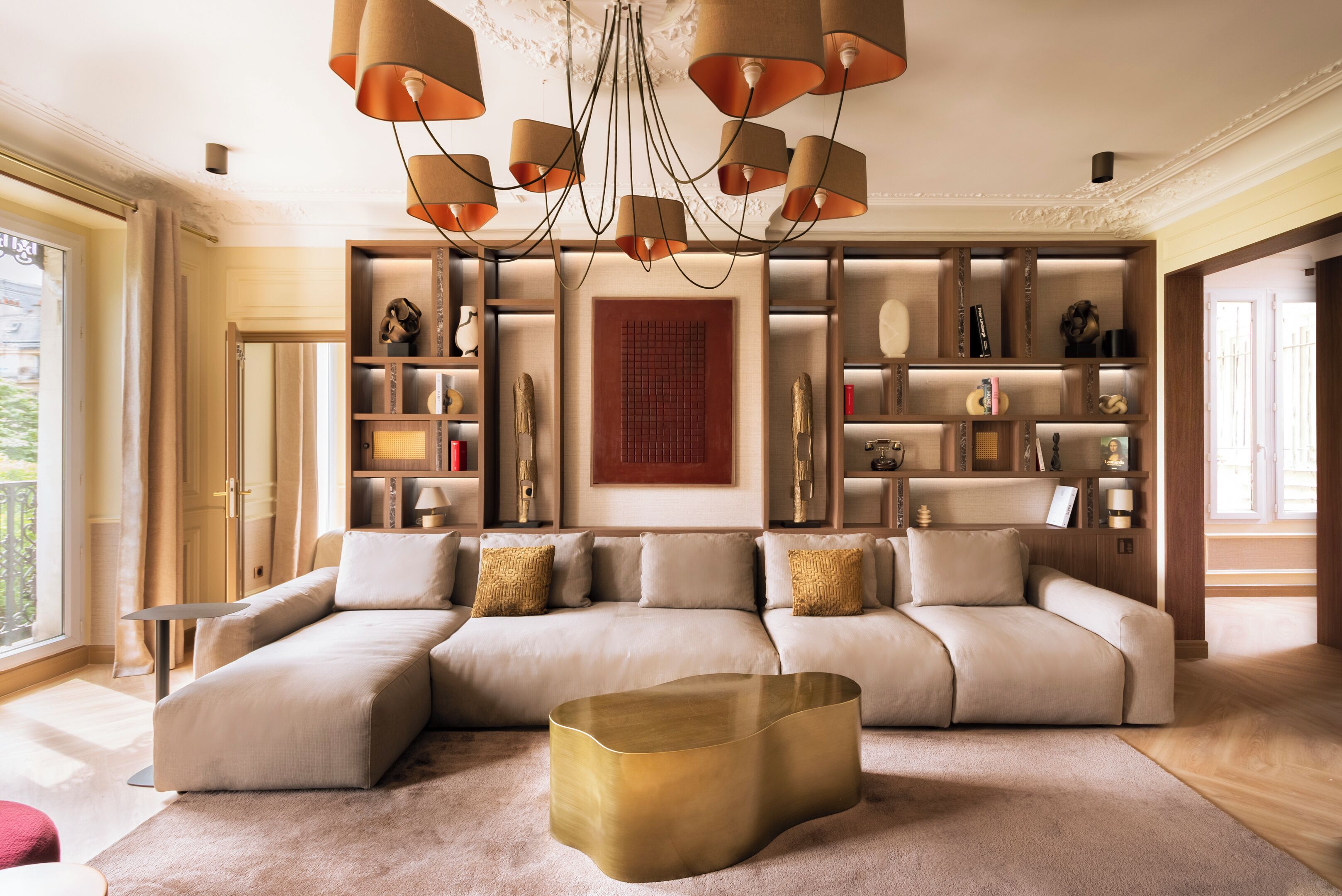 Un salon moderne avec un canapé d’angle, une table basse et un lustre décoratif.