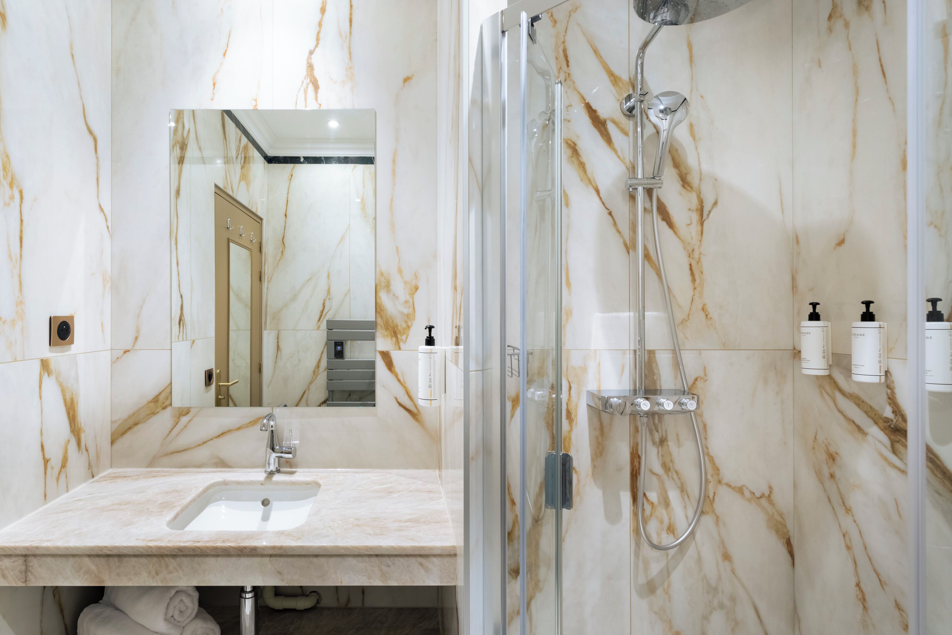 A bathroom with a marble sink, a glass-enclosed shower, and a mirror.