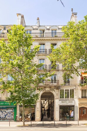 A multi-story building with a storefront labeled 'SKIN CHIC' and a green awning with graffiti. - Merveil Luxury Suite - Marais - Ponceau (Paris)