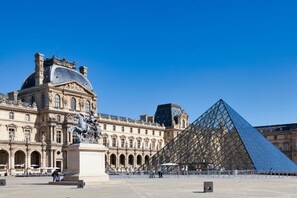 A large historic building with classical architecture and a modern glass pyramid structure. - Merveil Luxury Suite - Marais - Ponceau (Paris)