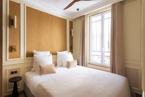 Habitación de hotel con una cama grande, una mesita y una ventana con cortinas.