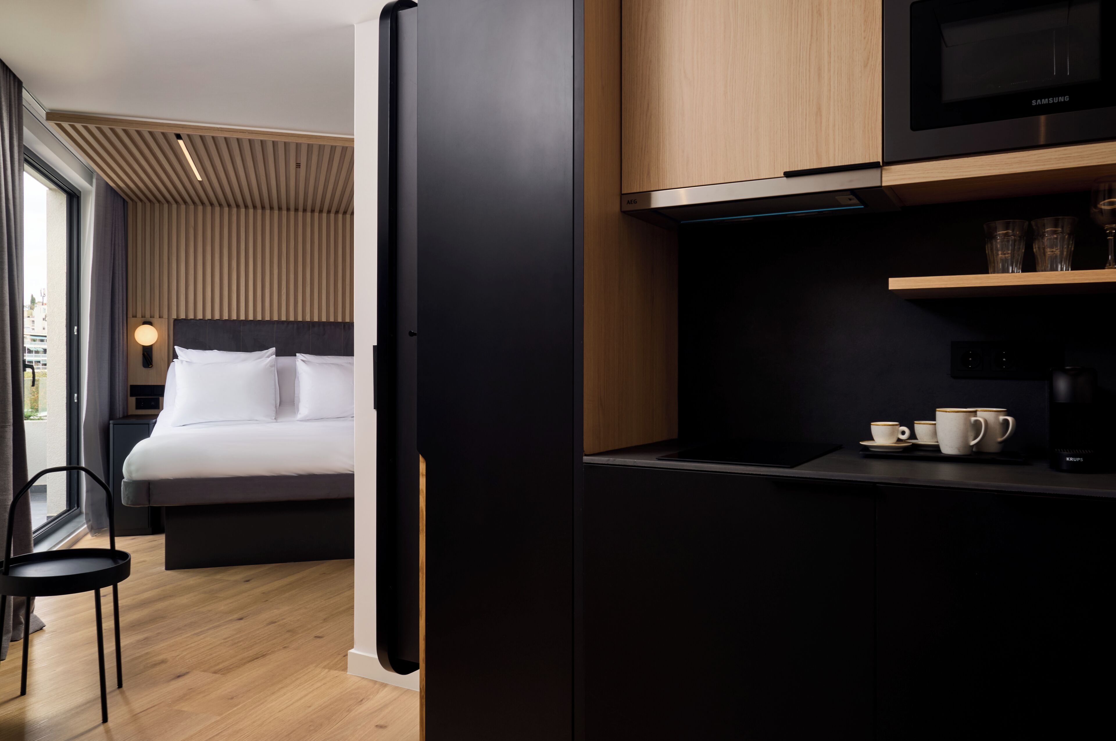 Una habitación de hotel moderna con una cama, un escritorio, un microondas y una cafetera.