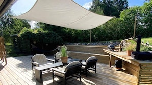 A wooden deck with outdoor furniture, a barbecue grill, and a large umbrella providing shade. - 5 Star Holiday Home in Knebel (Knebel)