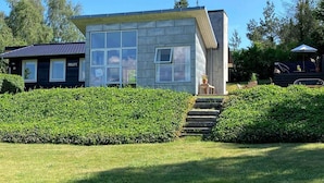 A modern house with a large window, a small porch, and a well-maintained garden. - 5 Star Holiday Home in Knebel (Knebel)