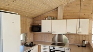 A compact kitchen with wooden walls, a stainless steel sink, a Bosch oven, and a Siemens refrigerator.