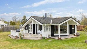 A two-story house with a covered patio, a chimney, and a fenced backyard.